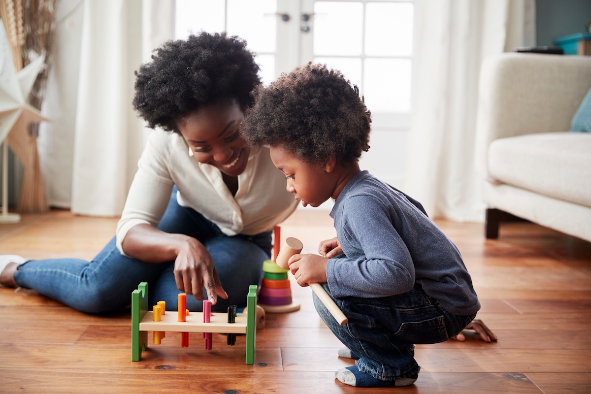 Mother And Young Son Playing With Wooden Toy At Home