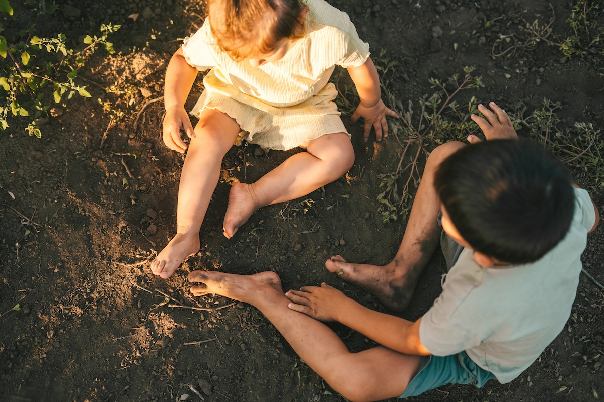 Top view of two dirty children resting on the ground after helping their parents work in the vineyard. Beautiful kids playing vineyards, great design for any